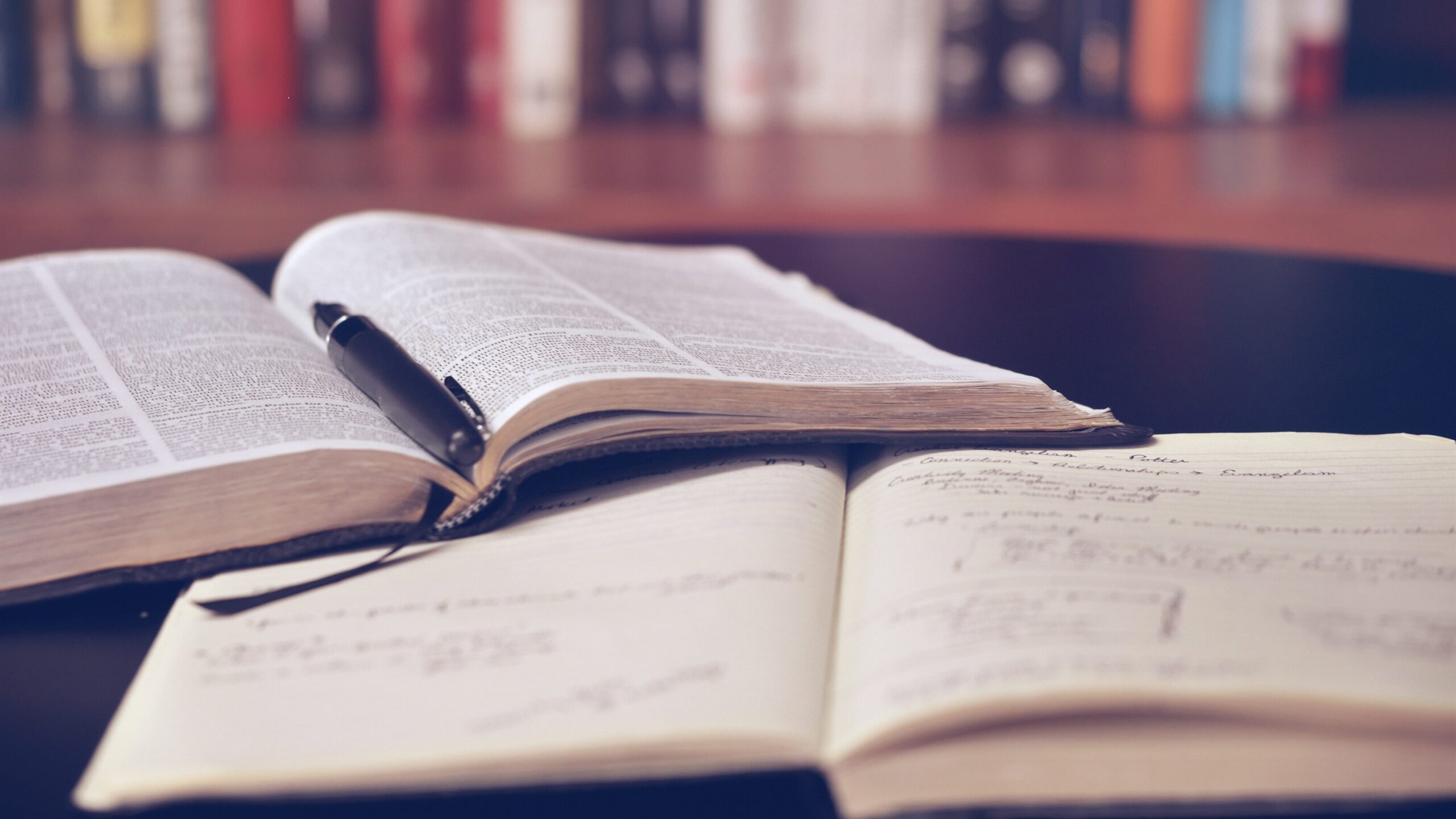 Picture of an open dictionary lying on top of an open notebook